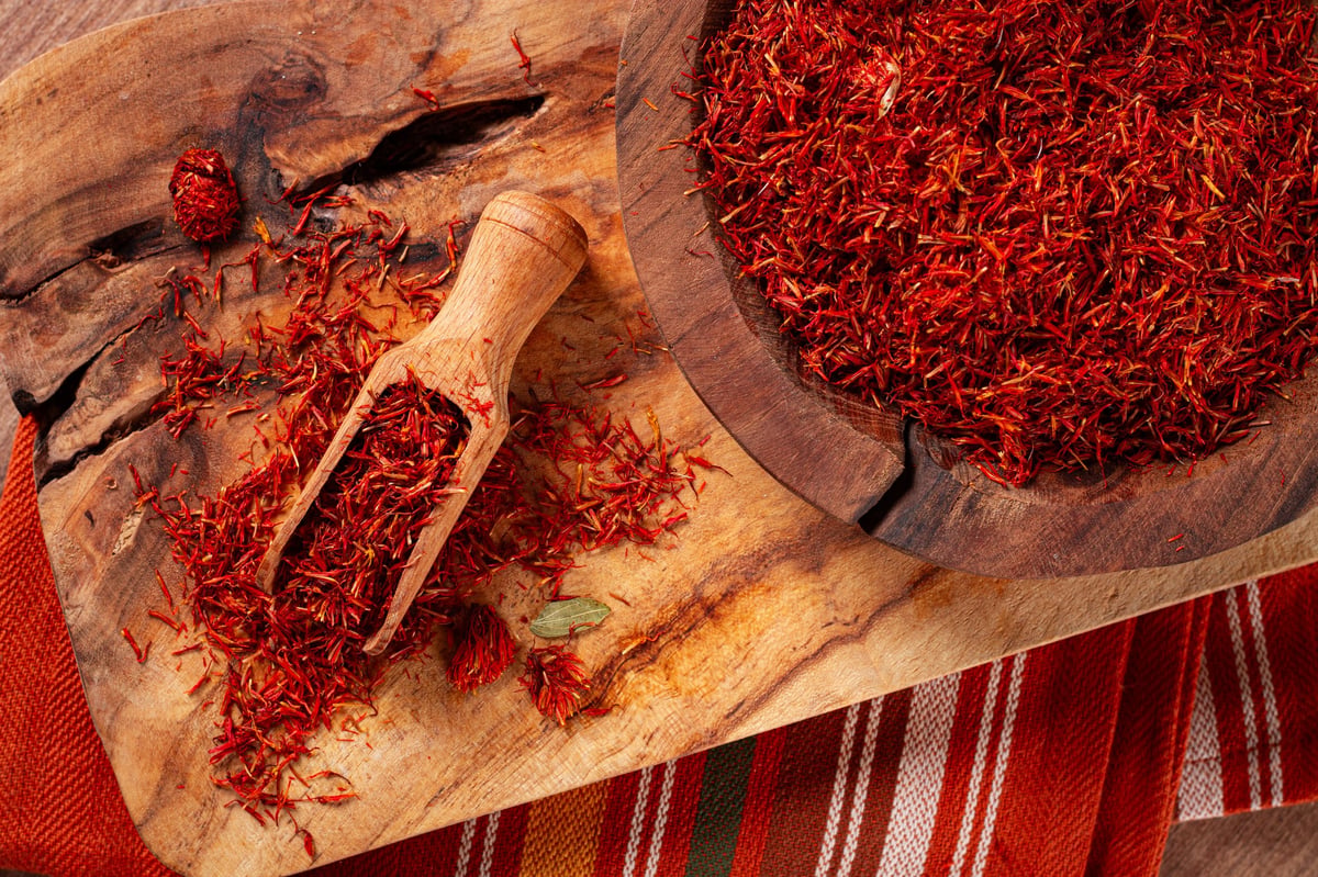 Spice saffron threads, in a wooden bowl, on a wooden table, top view, close-up